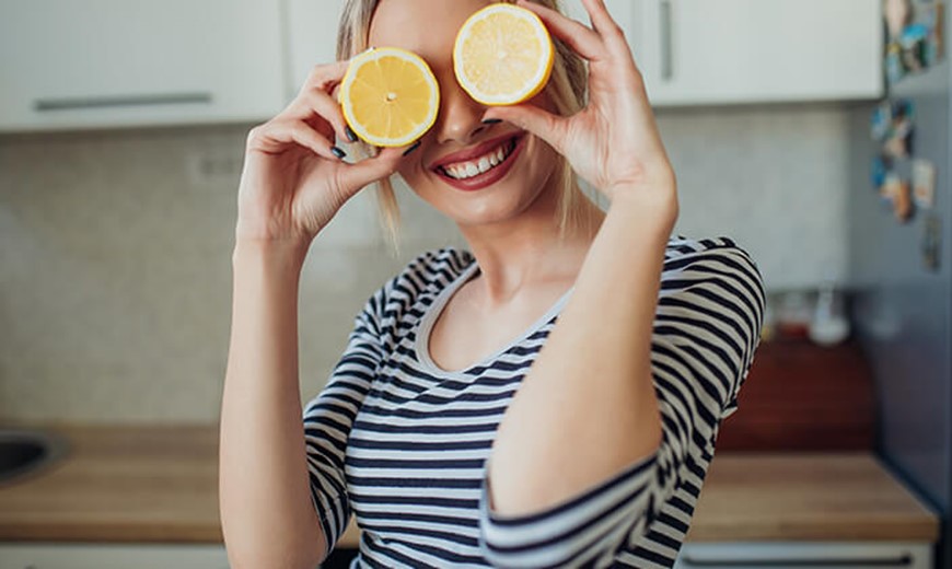 Frau hält Zitronen vor die Augen Vitamin-C-Mangel kommt sehr selten vor